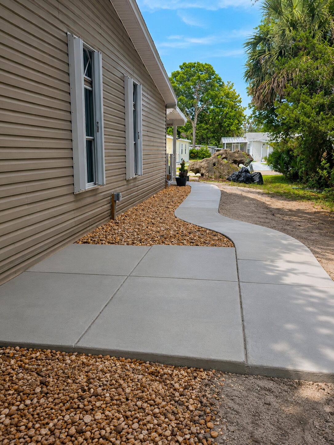 Fresh curved concrete sidewalk with a shed floor pad beside a home