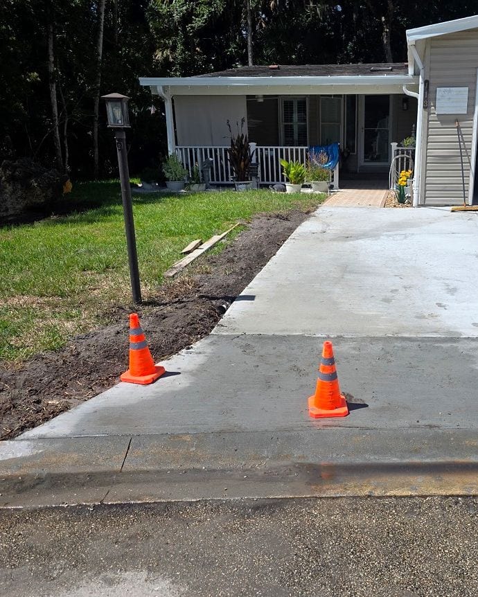 Finished concrete driveway extension leading toward the front entry