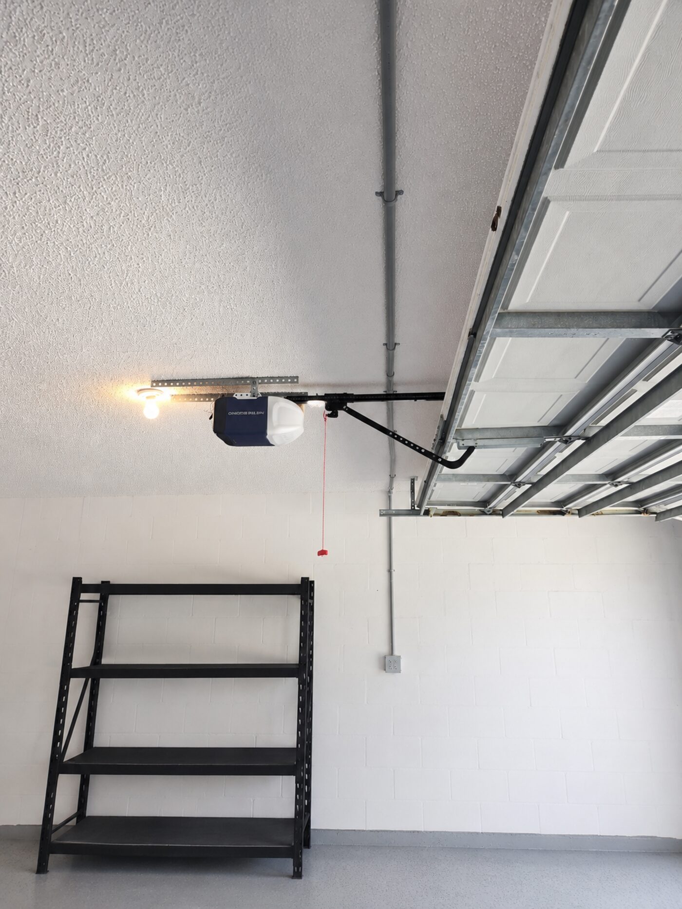 Surface-mount conduit running along a garage ceiling with the Chamberlain opener visible