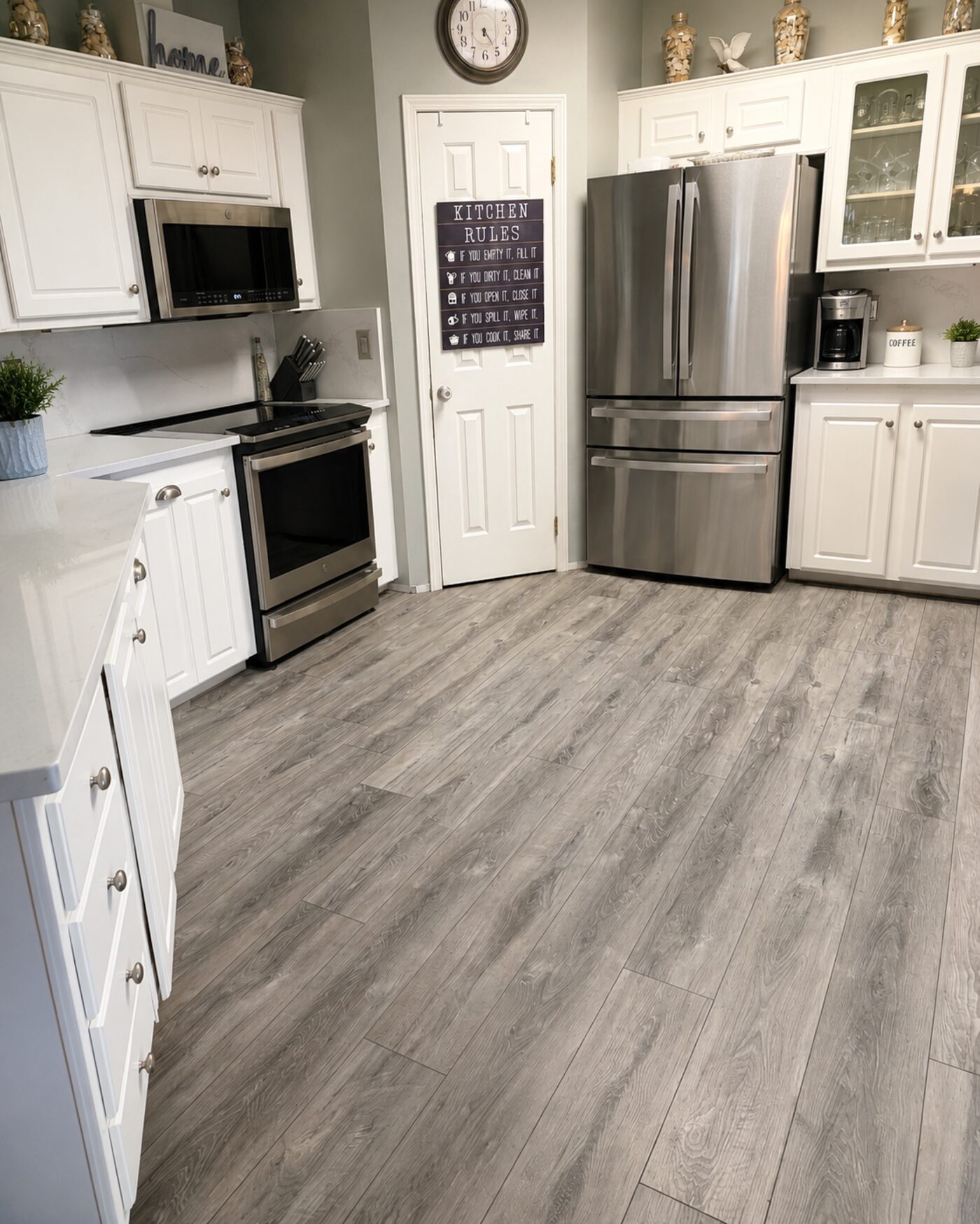 Luxury vinyl plank flooring in a kitchen with stainless-steel appliances and white cabinets