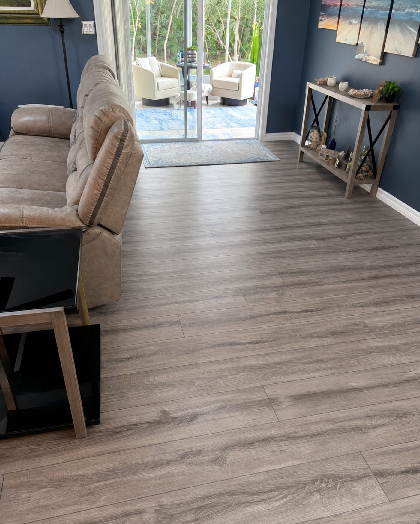 Luxury vinyl plank flooring installed in a living room with a sliding-door patio view
