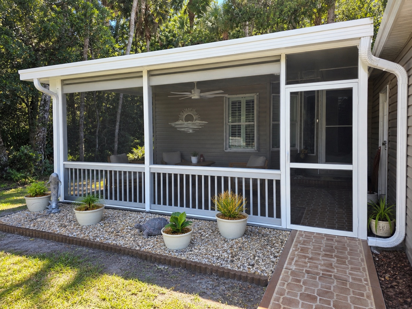 Screened porch with potted plants and brick walkway